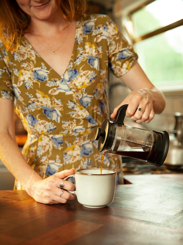 一个女人将咖啡倒入杯子。
