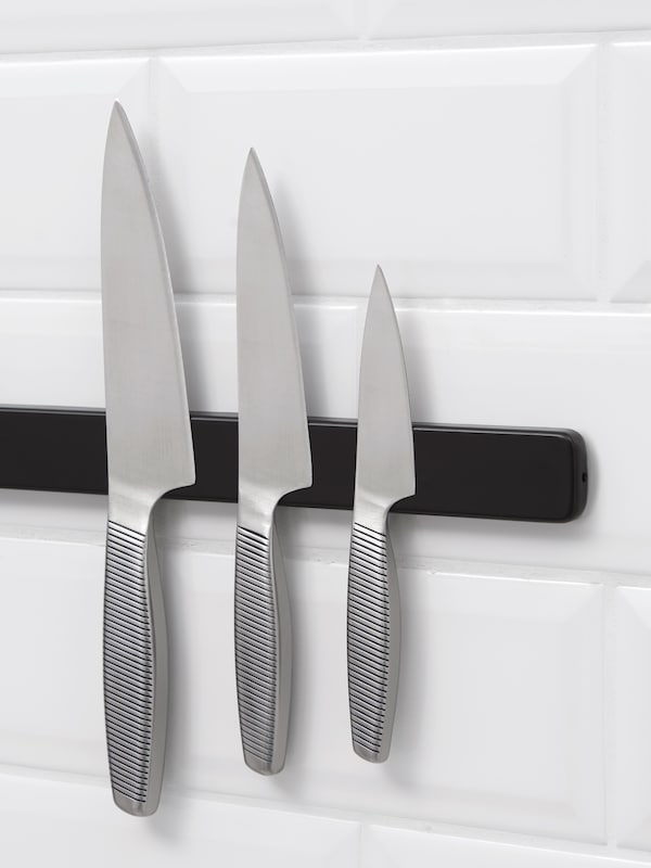 黑色磁性刀架持有三个不同大小在不锈钢厨房刀具。