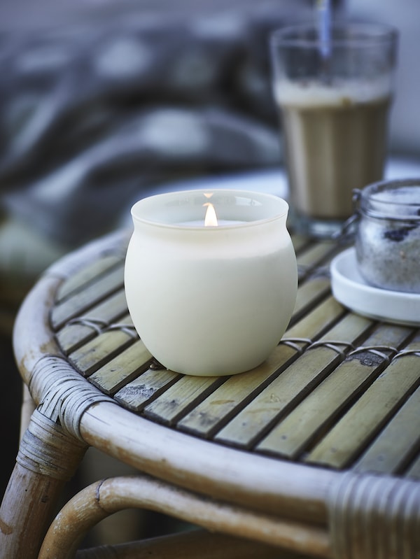 浅米色JAMLIK香味蜡烛在一个玻璃罐和一杯咖啡站在一张桌子天然材料制成的。