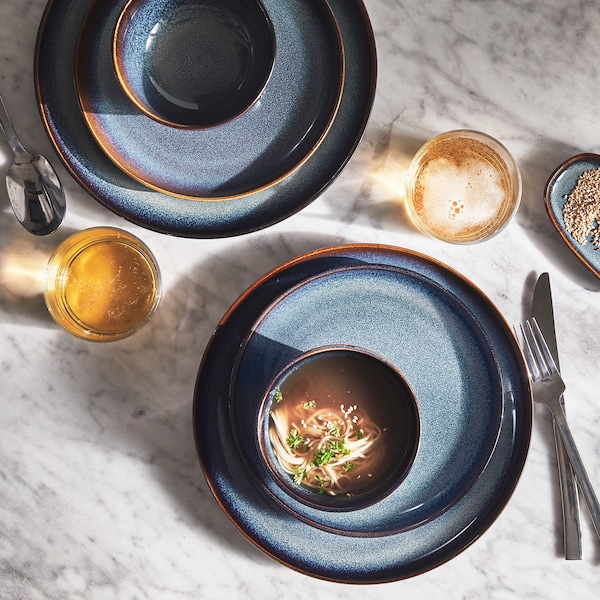 两个穿蓝色军装的GLADELIG碗持有多样化的食物GLADELIG盘子在桌子上刀,叉和勺子。