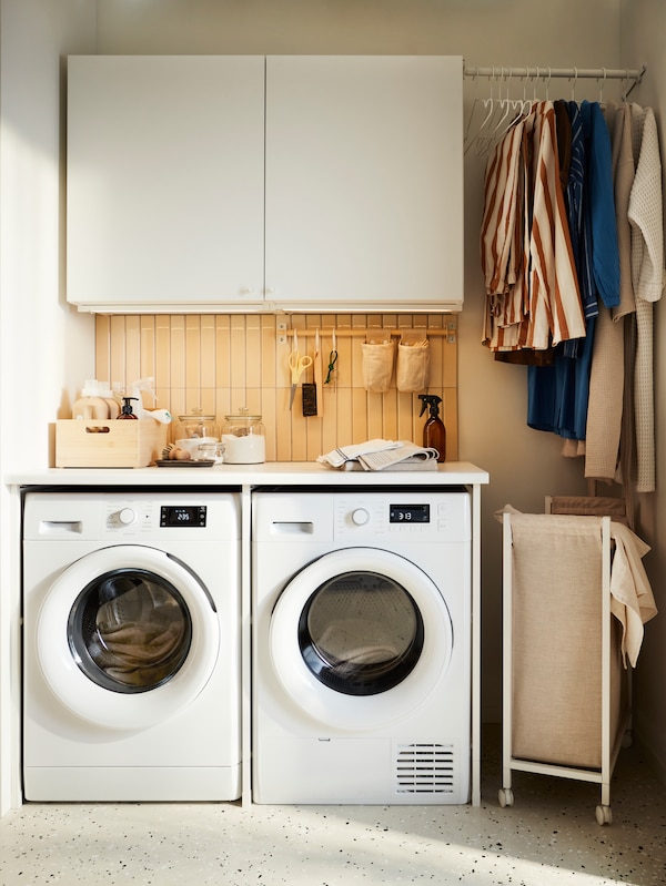 En ENHET vasketøjskombination placeret sammen地中海En UDDARP vaskemaskine, En UDDARP tørretumbler og tøj, der hænger直到tørre。
