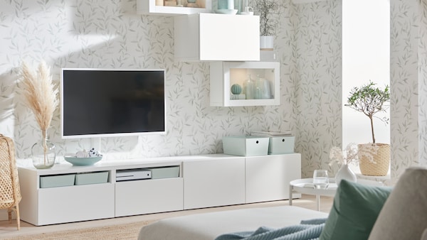 静脉weißes BESTA Aufbewahrungssystem steht在einem Wohnzimmer。Daruber hangt静脉Fernseher der魔杖。