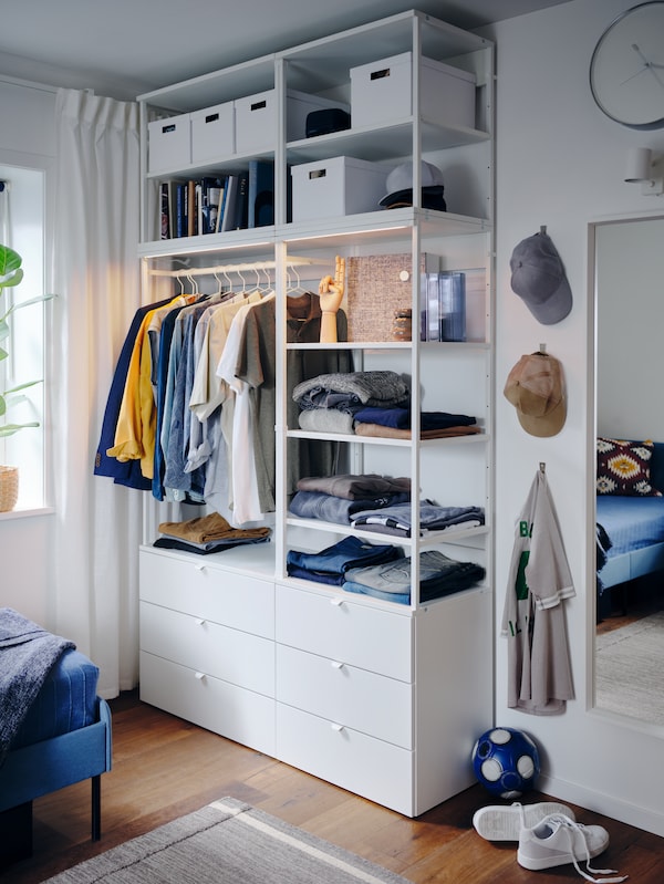 一个白色的衣柜与开放和封闭的存储、集成照明,衬衫衣架,折叠的裤子,帽子,白色盒子。