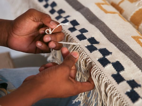 印度工匠的手中编织地毯的边缘的白色,蓝色,灰色和芥末。