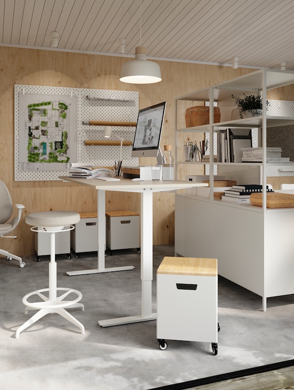 TROTTEN坐/站桌子前面LIDKULLEN积极坐/站支持在一个明亮的白色工作室开放的架子。