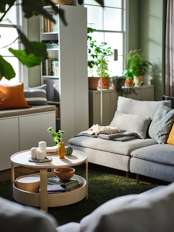 三的温柔阳光客厅beige-and-brown SODERHAMN开放式沙发,绿叶植物和绿色VINDUM地毯。