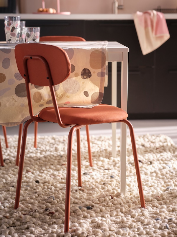En rødbrun OSTANO kjøkkenstol ved et dekket spisebord。