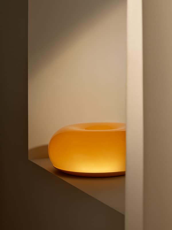 明信片VARMBLIXT LED-Tisch——/ Wandleuchte Donut-Form steht auf einem niedrigen Fensterbrett。您是eingeschaltet leuchtet。