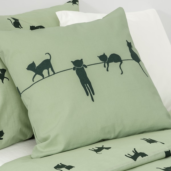 两个枕头在绿色BARNDROM枕套与一只猫躺在床模式匹配的床单和白色的垫子。