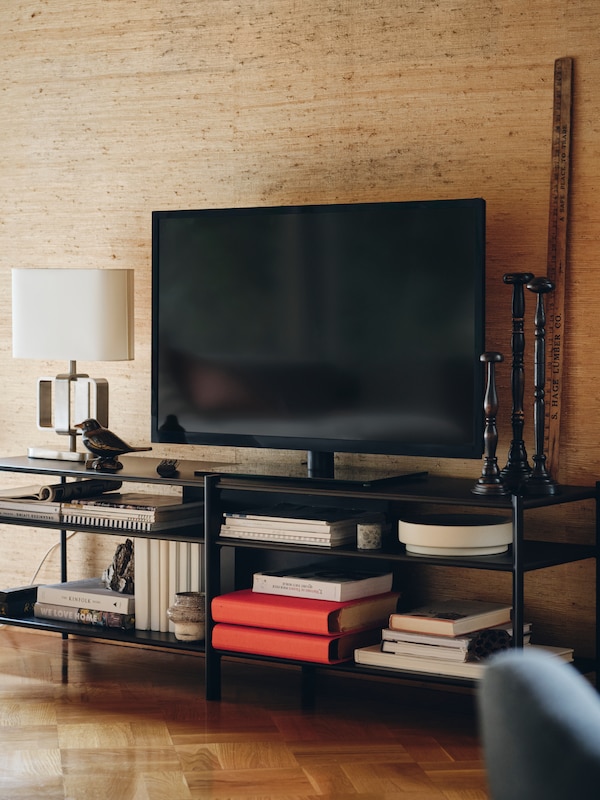 电视单位被放置在黑色JATTESTA电视上,各种书籍和装饰货架上商品的原因。