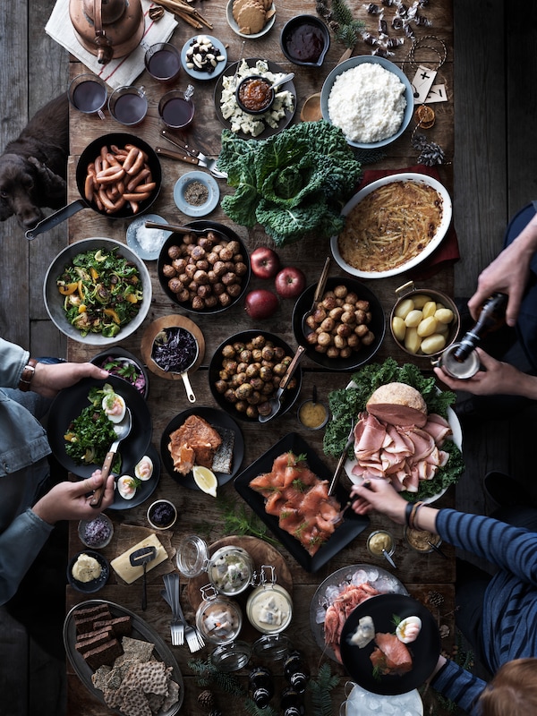 En gruppe mennesker sid omkring spisebord, hvor der服务器En traditionel瑞典julemiddag。