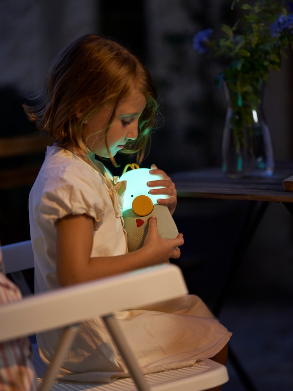 静脉类型sitzt im Dunkeln auf einem TORPARO Ruhesessel和停止杯leuchtenden VAPPEBY Bluetooth-Lautsprecher im的手臂。