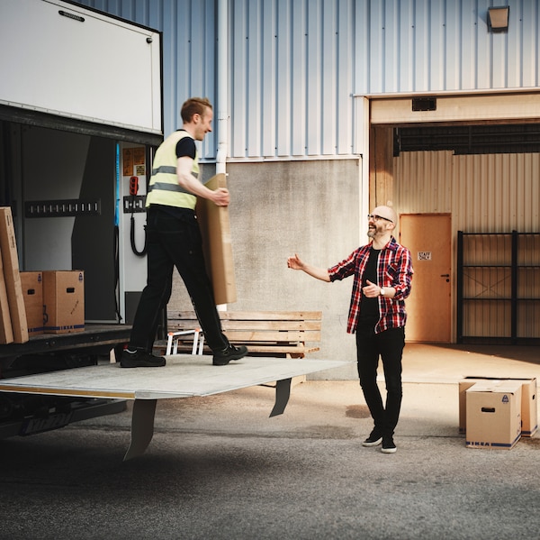 一个工人在一辆运货卡车给一个盒子一个人站在办公室的前面。