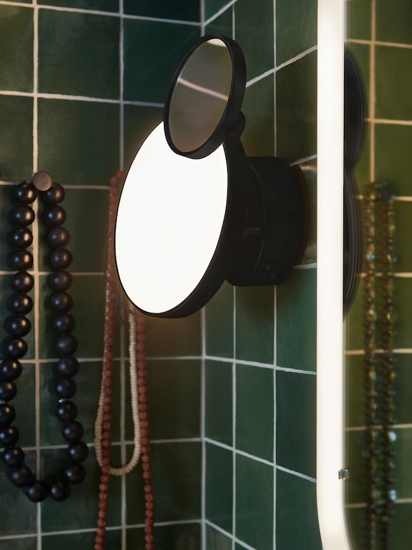 黑色KABOMBA壁灯和镜子,镜子旁边白色与集成照明和两个钩子拿着项链。