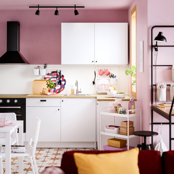 厨房用粉色的墙,马赛克地砖,KNOXHULT厨房角落,黑色家电和电车盒子和瓶子。