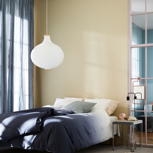 与STRANDTRIFT RISBYN吊灯挂在床旁边的床单HILJA窗帘的窗户。
