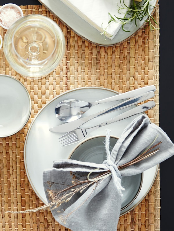 GLADELIG盘子,碗,一些餐具和餐巾,坐在附近的一个地方垫板夹持一块奶酪。