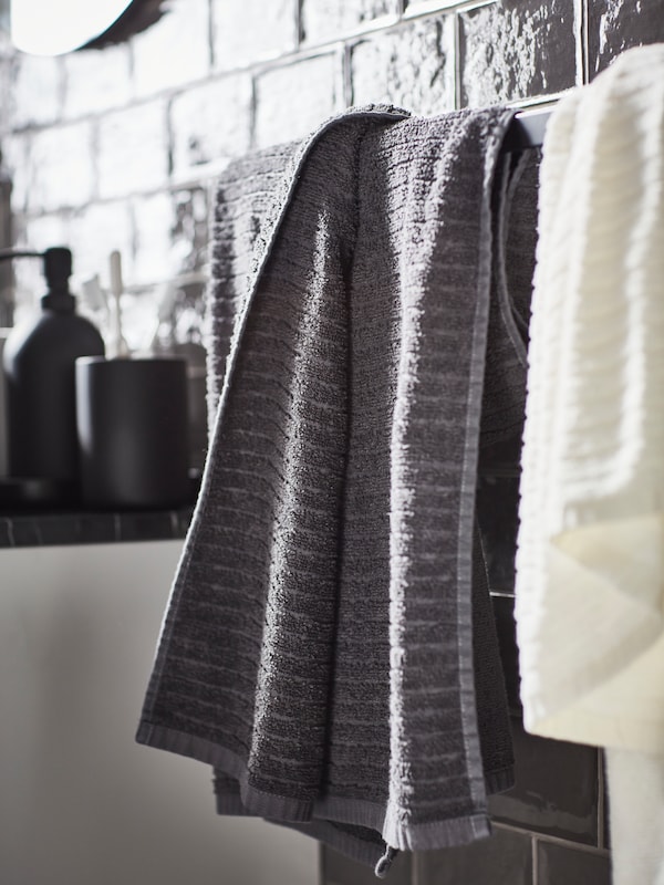白色和深灰色VAGSJON浴巾一个黑色的挂毛巾的横杆上墙灰瓦,加上一套陶瓷浴室三件套。
