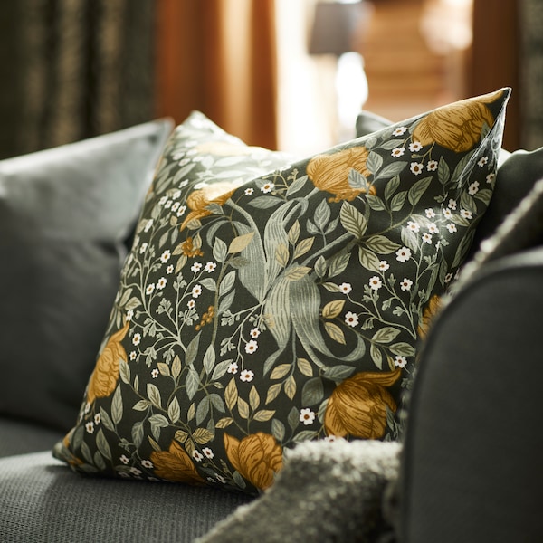 一个艺术和crafts-inspired绿色花卉TUVSAV靠垫设计的汉娜Wendelbo坐落在一个灰色的沙发。