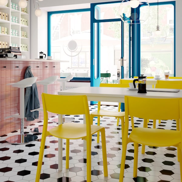一个通风的咖啡馆室内白色JANINGE酒吧凳一个计数器和黄色JANINGE椅子在白TOMMARYD表。