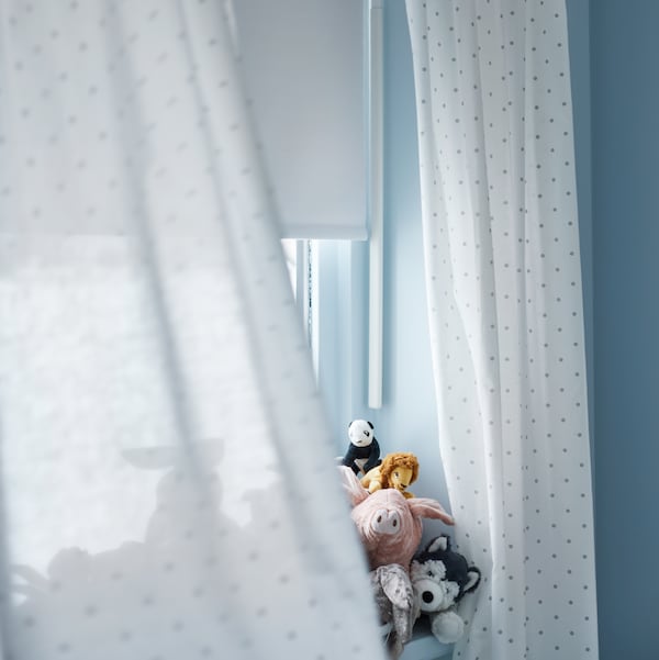 两个LEN窗帘和一个FRIDANS遮光窗帘挂在一个窗口。各种毛绒玩具能从背后的窗帘。