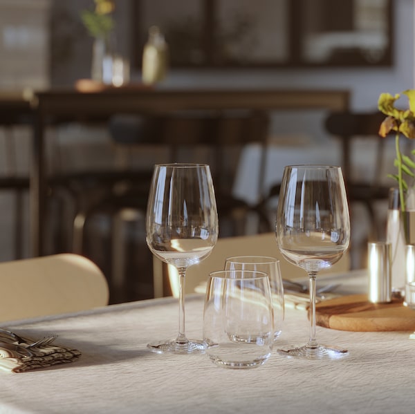 的特写STORSINT酒杯显示在一个表与水眼镜,餐具和一个小瓶一朵花。