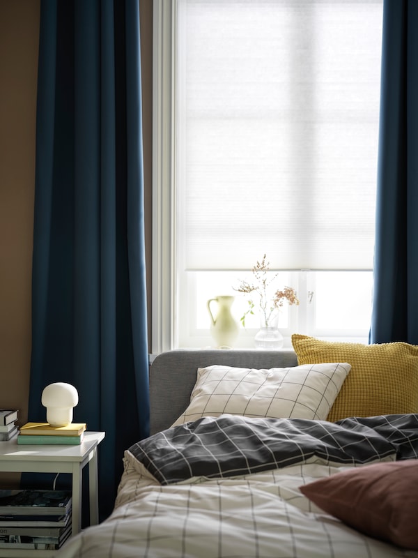 床上用VITKLOVER床单装有光遮光窗帘的窗口和蓝色HILLEBORG room-darkening窗帘。