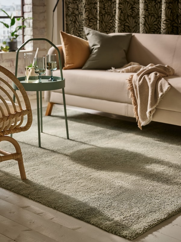 光灰绿色BURVIK侧表浅灰绿色SONDEROD高桩地毯,在米色沙发和靠垫。