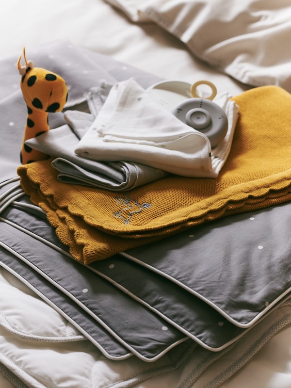 父母单位的UNDVIKA婴儿监视器坐在一堆纺织品包括深黄色SOLGUL毯子。