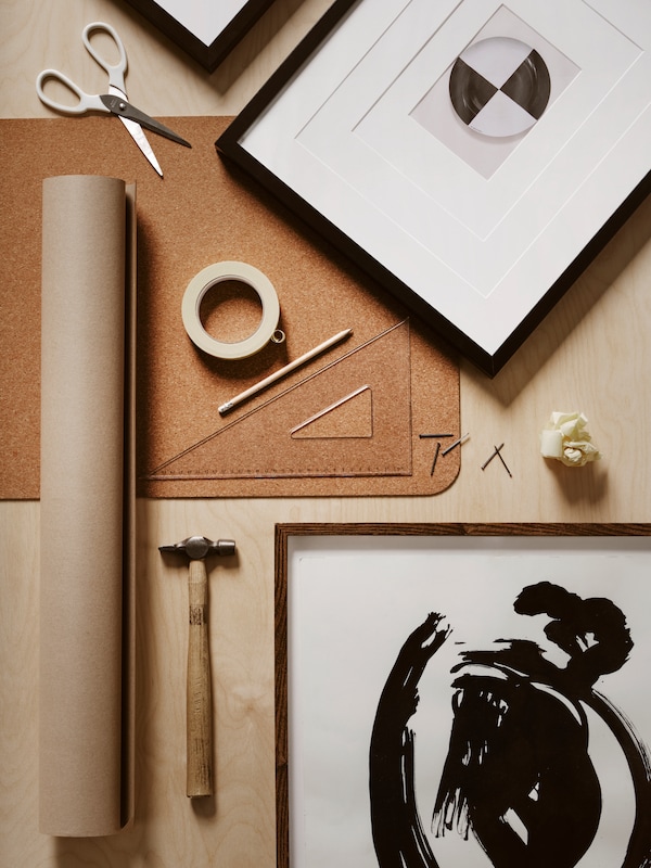 桌面和RIBBA LOMVIKEN帧,一卷牛皮纸,一卷胶带,剪刀、锤子、一把尺子和一支铅笔。