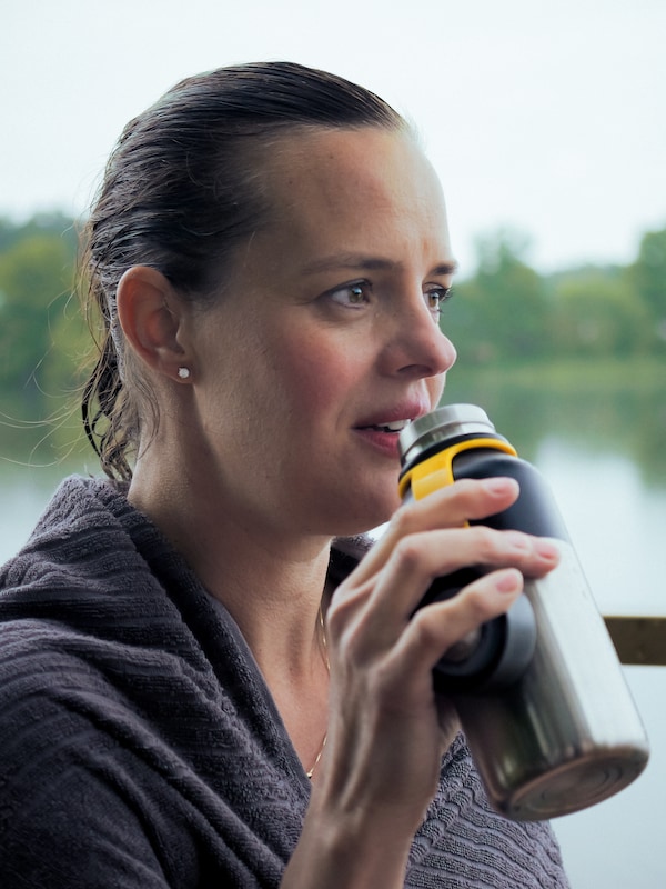一个女人坐在湖是HETLEVRAD绝缘瓶喝热饮。