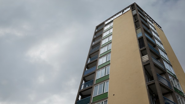 米色和绿色高层公寓大楼的角落阳台和窗户多云的天空。