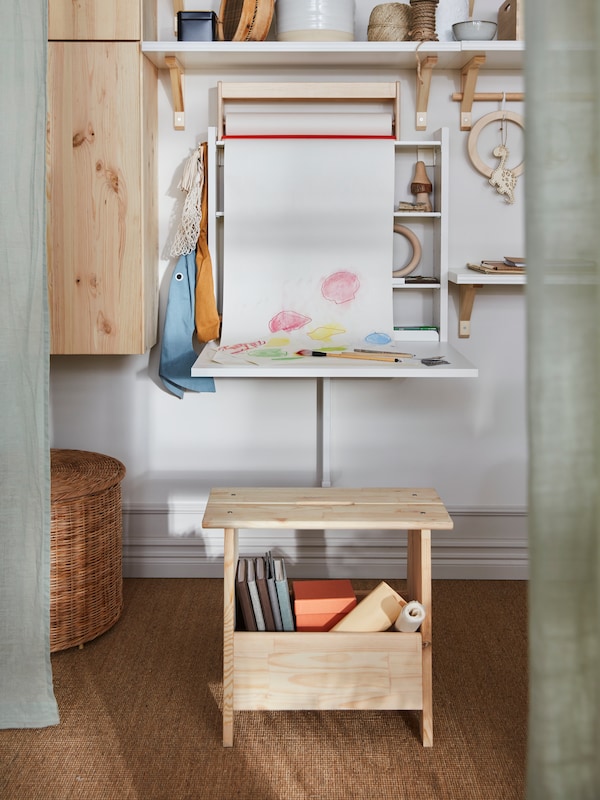 一个壁挂式NORBERG活动翻板桌面使用。一卷牛皮纸上面窗帘下来,显示了一个孩子的画。