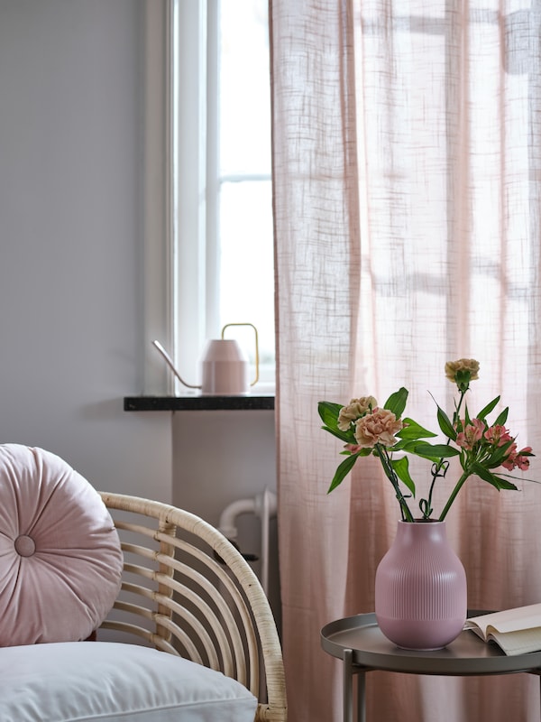粉色GRADVIS花瓶GLADOM托盘表旁边藤扶手椅上通过一个窗口亮粉红色SILVERLONN纯粹的窗帘。