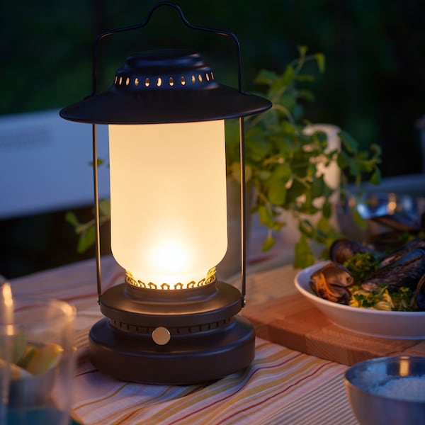 一架STORHAGA可控LED台灯放在户外的桌子,照亮了周围环境。