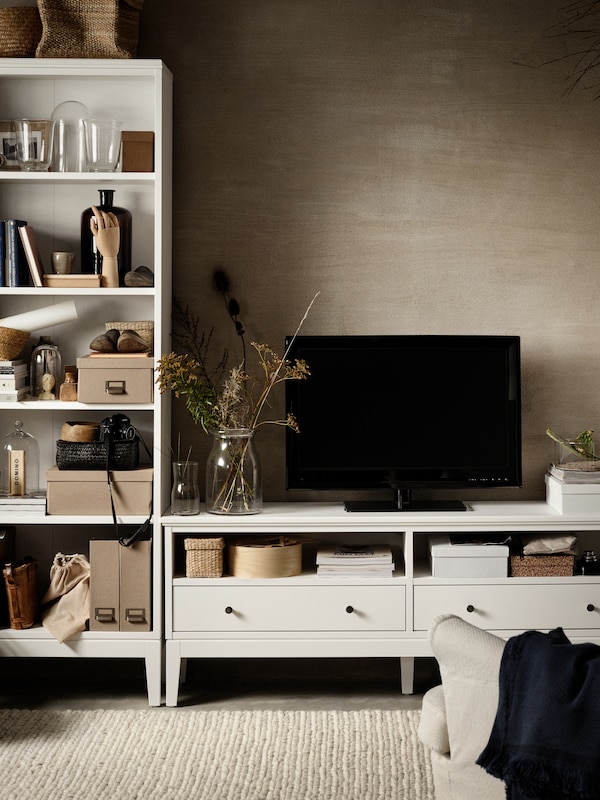 白色IDANAS书柜与盒子,杂志文件和装饰品。旁边站着一个电视白色IDANAS电视的长椅上。