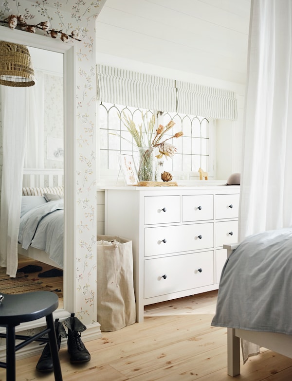 一个温柔的阳光照射的卧室木地板与white-stain HEMNES eight-drawer胸部和white-stain HEMNES床。