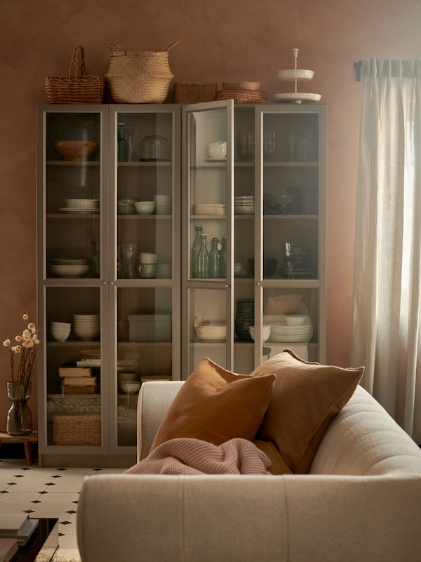两个比利书架玻璃门满餐具对apricot-coloured墙在一个乡村的房间里。