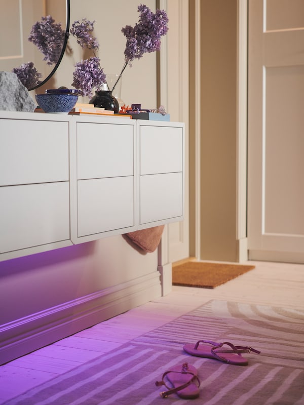 LEDBERG照明地带,下面三个EKET柜2抽屉安装在墙上,沐浴紫光的地板上。