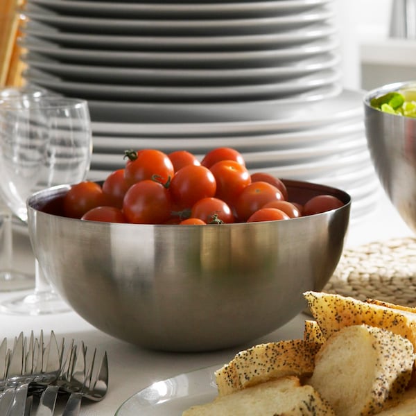 BLANDA空白不锈钢碗充满樱桃番茄,站在桌子周围面包和餐具。