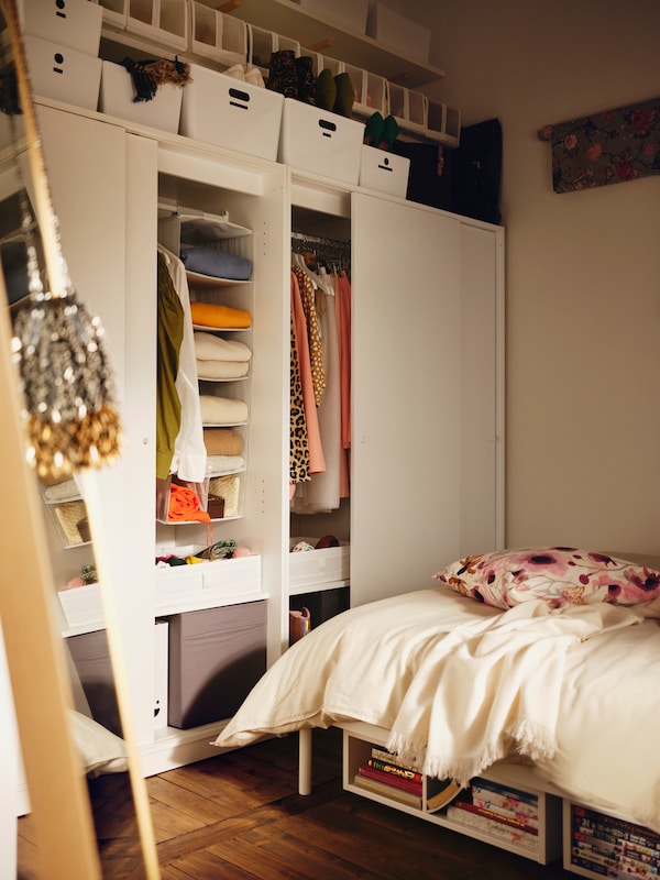 KLEPPSTAD床站在两个白人KLEPPSTAD衣柜滑动门包含衣服和许多盒子。
