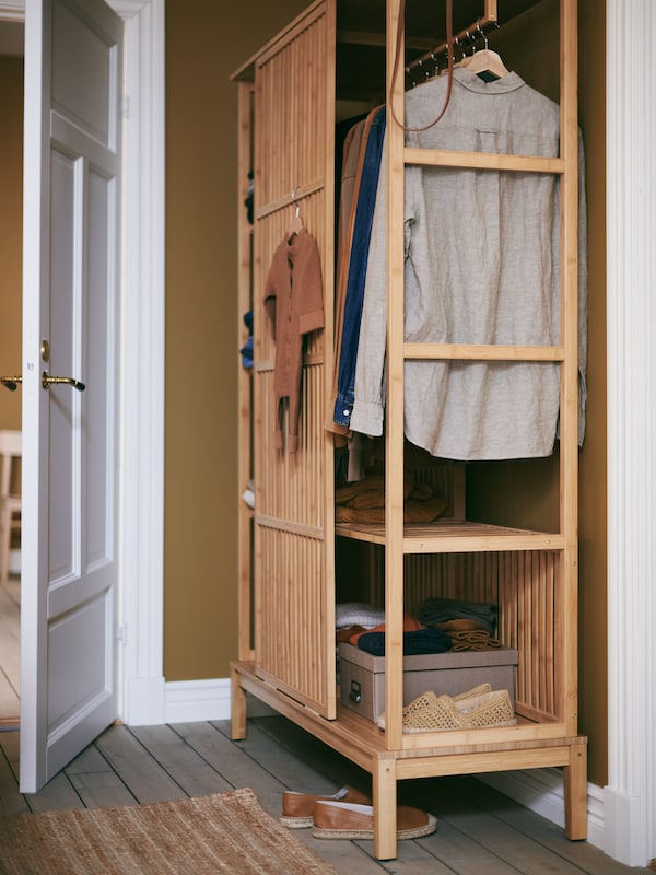 紧凑NORDKISA衣柜,旁边一个开放的白门,房子小衣架、花花绿绿的衣服鞋子和盒子。