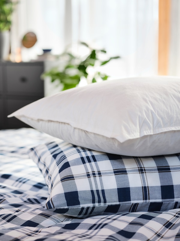 两个枕头放在床上的。枕头和床垫底部覆盖着SPIKVALLMO被套和枕套白色和蓝色。