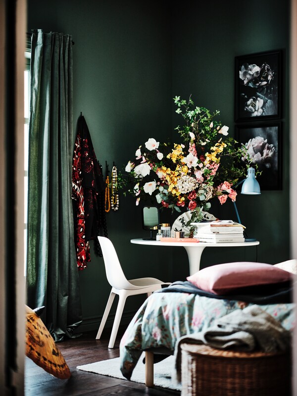 卧室的一个角落里有一把椅子ODGER和白色/白色DOCKSTA表和一个大的显示屏SMYCKA人造花。