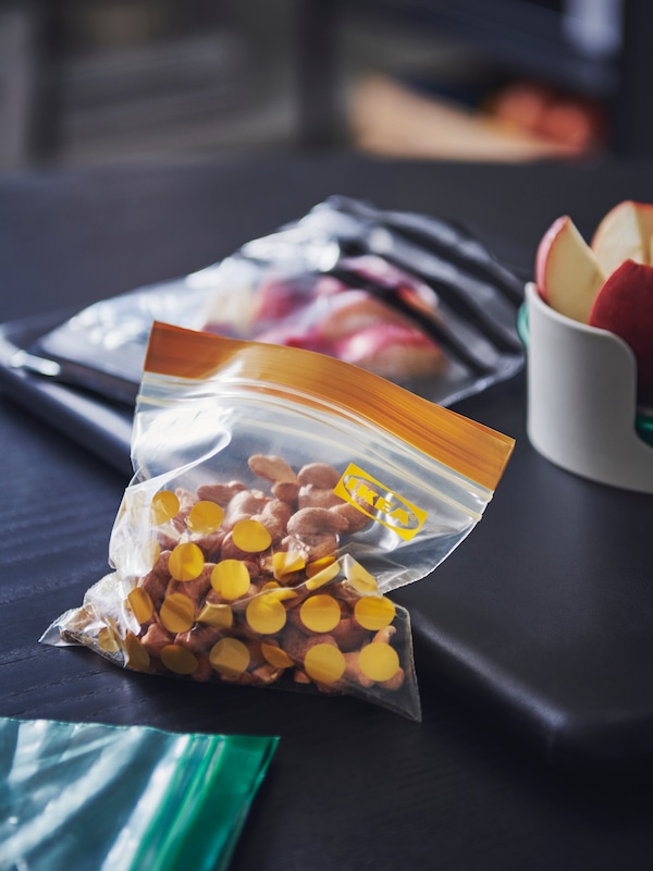 三个ISTAD可密封的塑料袋在不同大小不同食品在黑暗的木质表面,一个文件夹和其他物品。