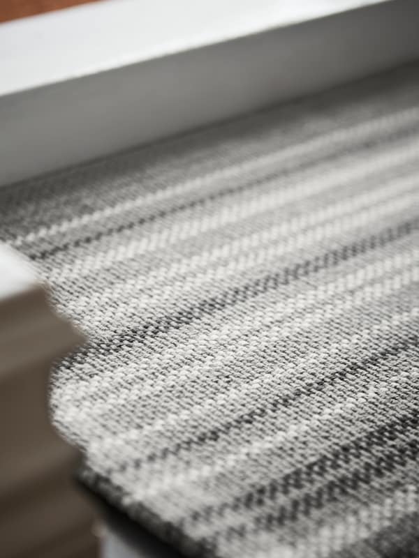 灰色/条纹的平纹地毯紧紧地贴在白色门框的底部边缘。