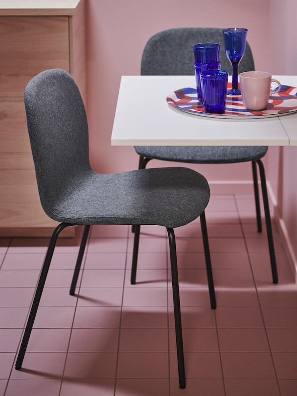 两把椅子由黑色SEFAST底架和浅灰色KARLPETTER座壳的小桌子pink-tiled房间。