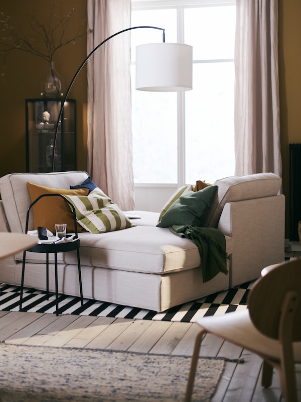 一个客厅和两个米色KIVIK马车过来与缓冲窗口,在斯德哥尔摩flatwoven地毯。