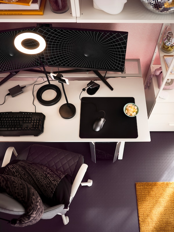 游戏把椅子和一个灰色游戏桌子前面的一个粉红色的墙持有两个显示器,键盘和LANESPELARE环光。