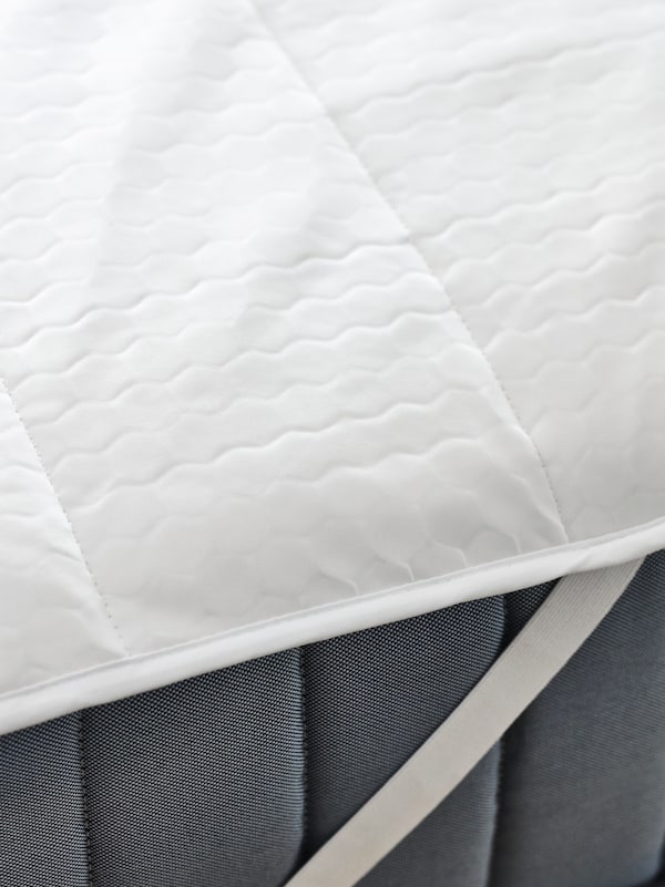 VALEVÅG弹簧床垫的顶部和侧面，顶部有白色ROSENVIAL床垫保护器。
